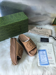 GG SLIDE SANDALS IN CAMEL BROWN RUBBER EMBOSSED LOGO